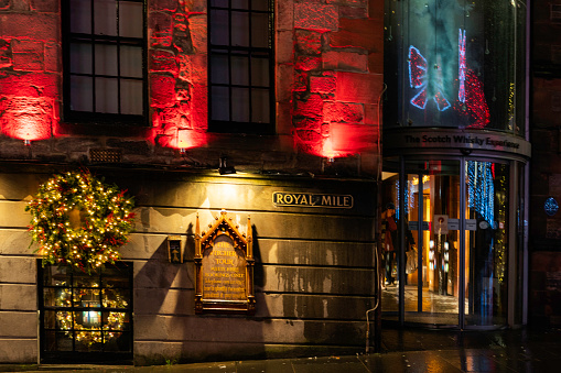 Edinburgh, Scotland, UK - December 10, 2022: Exterior of buildings on a rainy night in Old Towne during the Christmas season.