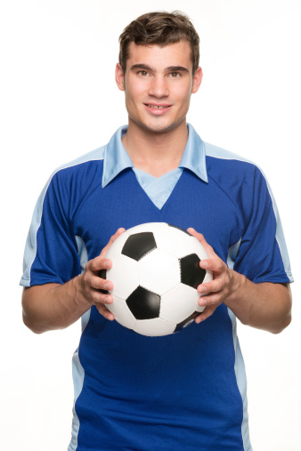 Young soccer player with ball in front of white background