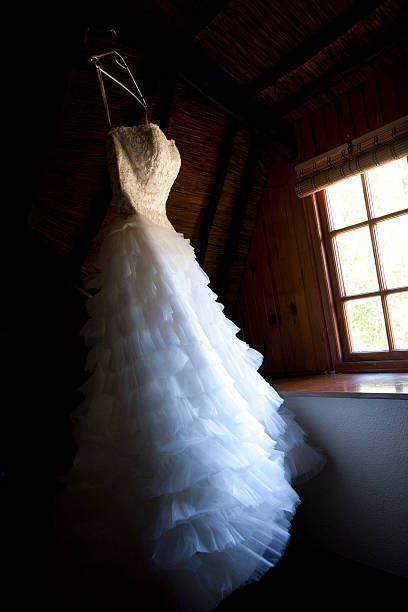 Vestido de casamento pendurado em uma janela - foto de acervo
