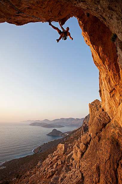 rock alpinista ao pôr do sol - climbing men sea cliff imagens e fotografias de stock