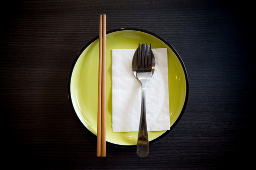place setting with chopsticks fork spoon mouth paper on green dish