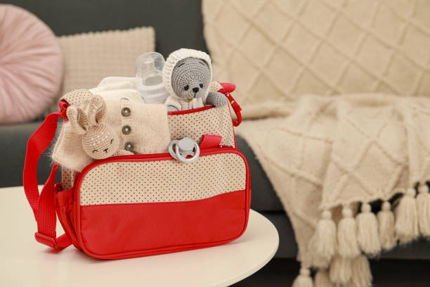 istock Mother's bag with baby's stuff on white table indoors. Space for text 1775101103