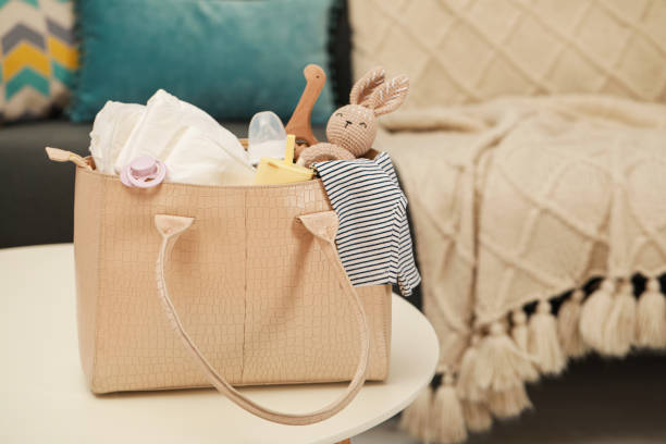 istock Mother's bag with baby's stuff on white table indoors. Space for text 1775101112