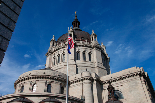 St Paul Cathedral vertical view with blue sky and clouds and American flag in front