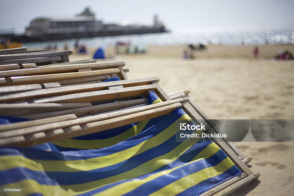 Deckchairs On Promenade "Folded pile of deckchairs on the promenade in Bournemouth, UK. Shallow focus with pier in background" Stack Stock Photo