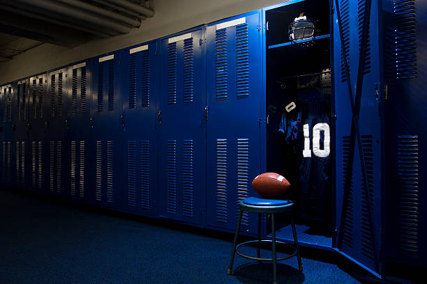 Football locker room with open locker An open locker with a jersey, helmet and ball in a authentic football locker room locker room stock pictures, royalty-free photos & images
