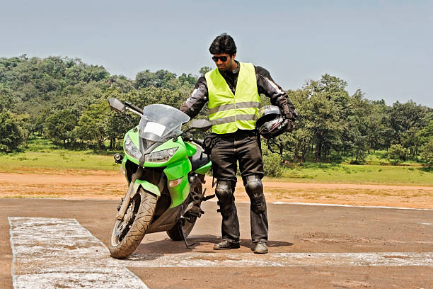 Motorcyclist riding on an open road in the hills among giant power lines and transformers. He is riding in the summer on a sunny day and showing determination and focus. He is fully suited up in safety equipment.