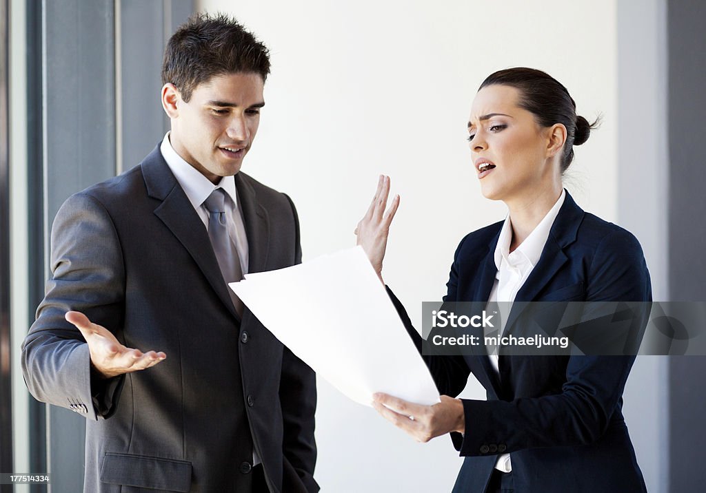 colleagues arguing over paperwork two young colleagues arguing over paperwork in office Arguing Stock Photo