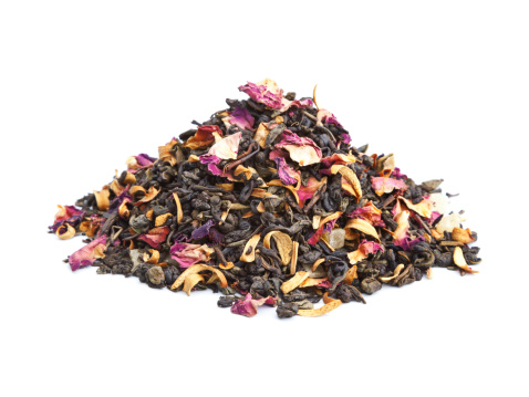 Elite green tea with candied fruit and rose petals on white background
