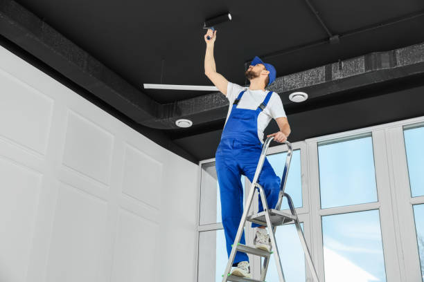 istock Worker in uniform painting ceiling with roller indoors, low angle view 1775145285