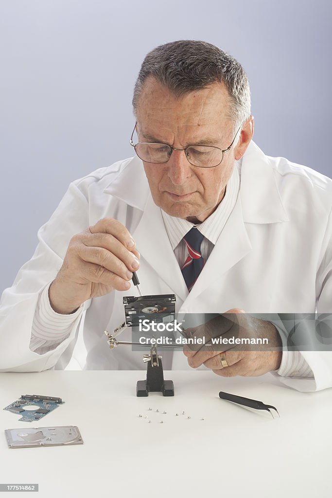 HDD Repairman "An older male wearing a white lab coat and repairing electronic equipments, like a technician or a repair man." Electrician Stock Photo