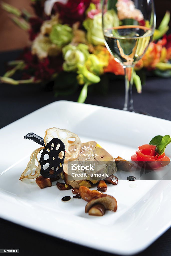 Goose liver on white plate with red rose garnish Juicy goose liver on a plate and glass of white wine Foie Gras Stock Photo