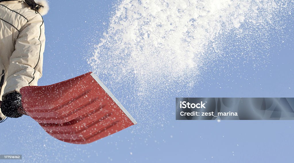 Person shoveling the snow in winter Throwing snow with a snowshovel against blue sky Snow Stock Photo