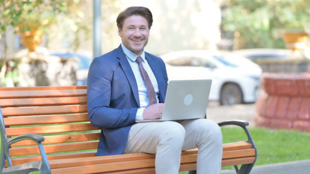 istock Businessman Smiling at Camera while Working on Laptop Outdoor 1775165481
