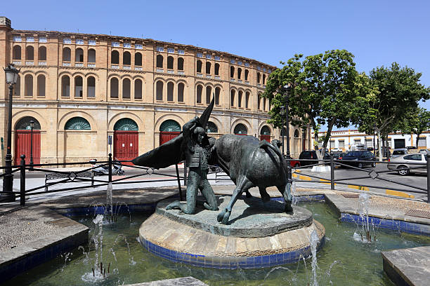 Vigo, Spain - November 22, 2021: Spain square in downtown Vigo, Pontevedra province, Galicia, Spain. Horses sculpture set on traffic circle,  Gran Vía avenue and retro style street lights in the foreground. Sunset sky background.