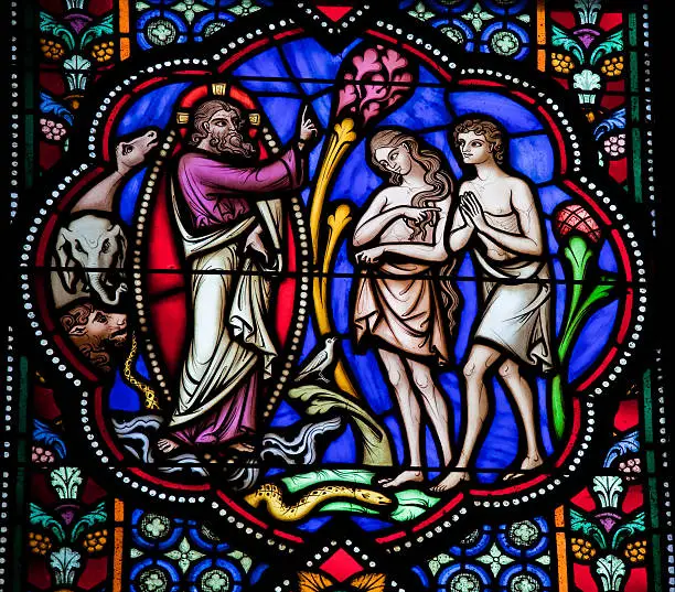 "Adam and Eve in the Garden of Eden. Stained Glass window in the cathedral of Brussels, Belgium. This window was created before 1870; no property release is required."