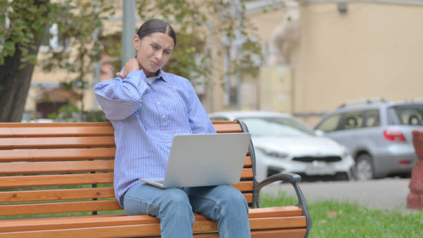 latin woman with neck pain working on laptop outdoor - 15851 imagens e fotografias de stock