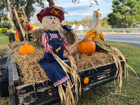 Hayride trailer filled with hay, scarecrows and pumpkins.  Autumn fun and decor.