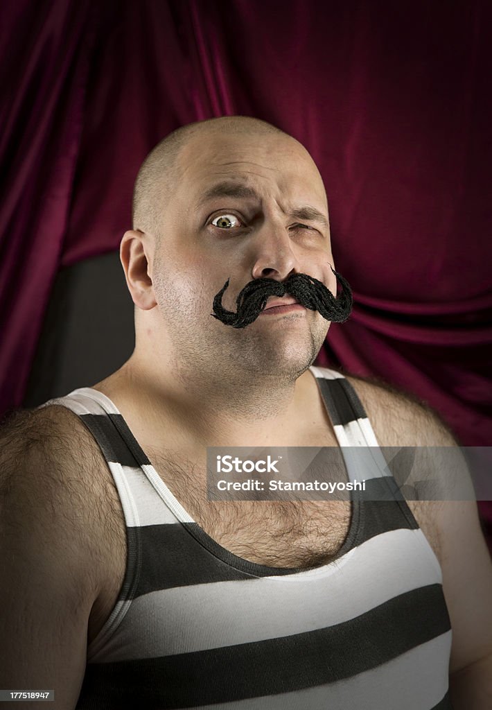 Vintage circus strongman with big mustache Vintage circus strongman with big mustache. Bald strong man with striped t- shirt. Part of larger vintage collection. Circus Stock Photo