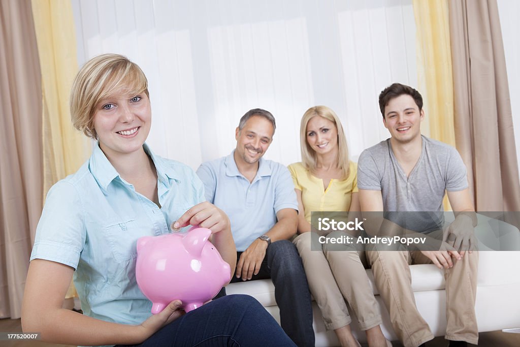 Saving for the future Attractive young teenage girl putting a coin in a pink piggy Adult Stock Photo