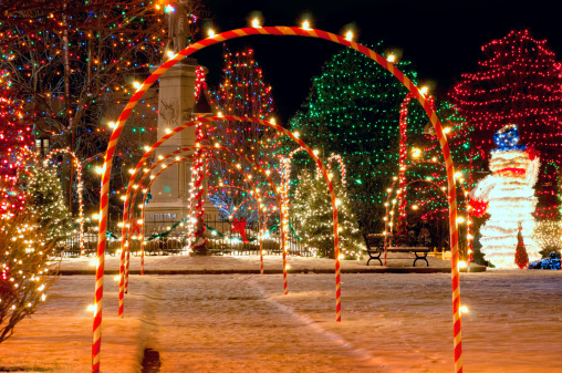 Pathway of candy cane arches leading to a brightly lit village Christmas display