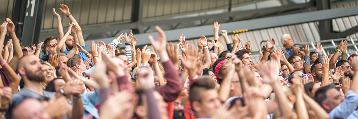 Football or soccer fans are cheering for their team at the stadium on the match