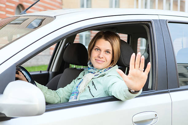 istock Woman greeting by hand and looking at camera from car 177521666