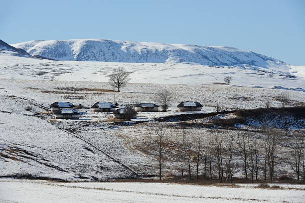 Drakensberg snowy hillside "Staff cottages on a farm in the Drakensberg foothills,Kwazulu Natal,South Africa against a fall of snow" drakensberg mountain range stock pictures, royalty-free photos & images