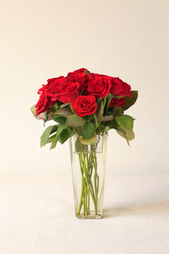 Red roses bouquet in vase on linen canvas background.