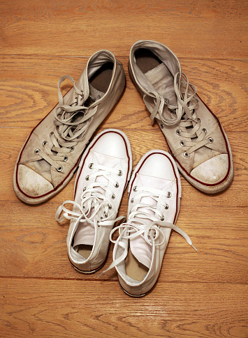 Big and dirty boy's shoes arranged around small and clean girl's shoes