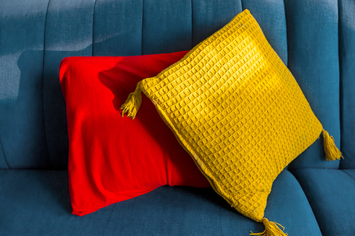 Horizontal shot of almost monochrome cushions, positioned on a beige, textile sofa, very modern, minimalist interior design detail for a cozy home.