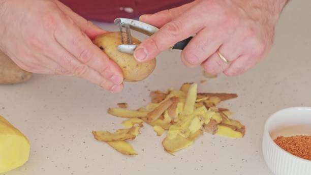 istock Caucasian Male Peeling Fresh Potatoes on Kitchen Worktop using Sharp Metal Peeler 1775269750