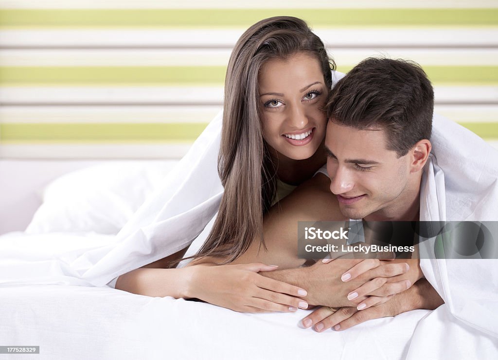 Heureux jeune couple sous la couette du lit - Photo de Adulte libre de droits