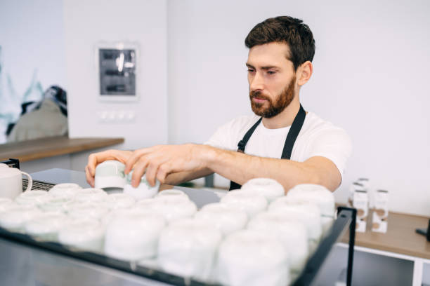 istock A serious, focused man stands at the bar, stacking clean white cups on a coffee machine. 1775286323