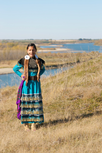 Portrait of a Jingle Dress Dancer in a prairie field with a river background