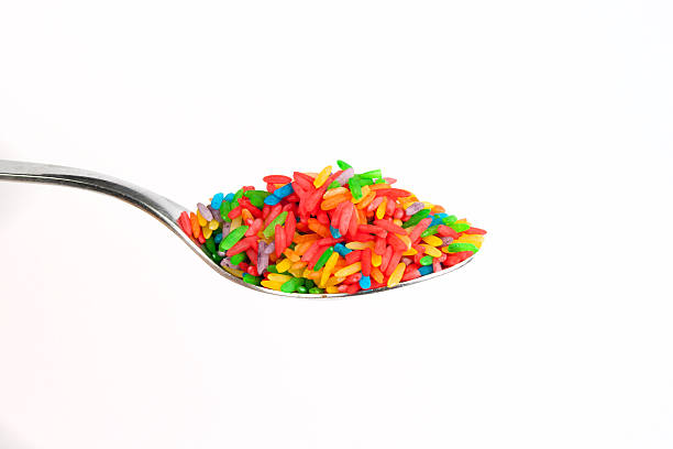 Rainbow Rice Spoonful of artificially colored rice against a white background.  food coloring stock pictures, royalty-free photos & images
