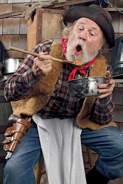 istock Hungry old cowboy eating beans from a saucepan 177529574