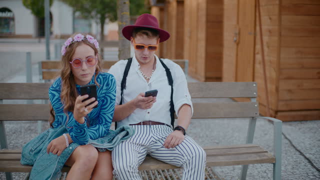 Young couple using smart phones on bench
