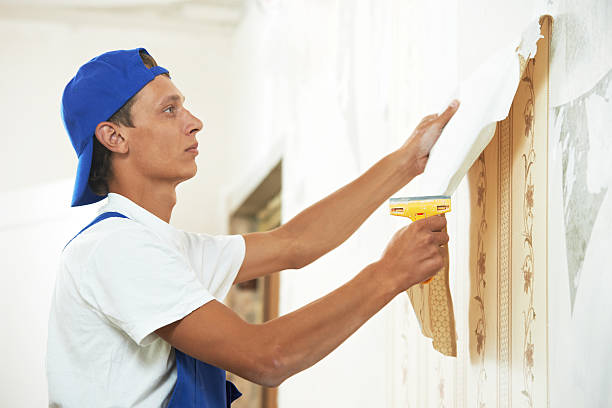 painter worker peeling off wallpaper stock photo