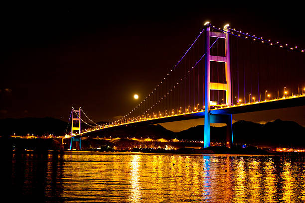 Nighttime view of Tsing Ma Bridge, Hong Kong "Hong Kong's Tsing Ma Bridge, this double deck suspension bridge connects Tsing Yi and Ma Wan Hong Kong. It is the 8th longest suspensions bridge in the world." hong kong moon night stock pictures, royalty-free photos & images