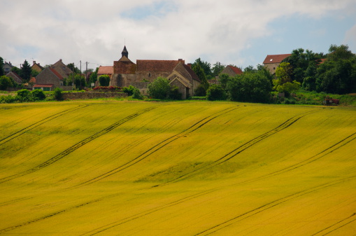 Montigny-lès-Condé, France - Jul 6, 2012: A typical small quiete french village placed at the top of a hill and a beautiful wheat field on its slope.