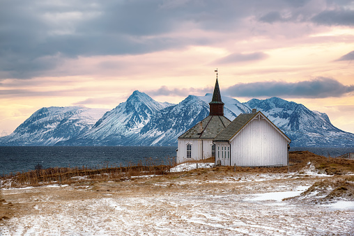 A church on the Lofoten Islands in northern Norway, winter landscape with the wooden small cathedral on the sea coast with mountains and dramatic sky