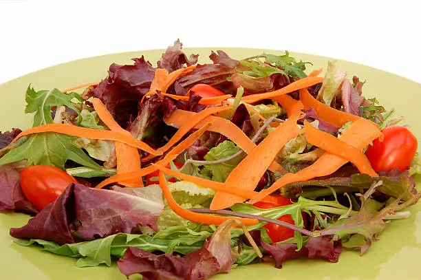 A healthy salad of carrots and tomatoes on a bed of greens