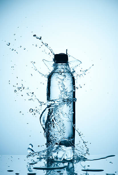 plastic bottle of water and splash around it Water splashed around a plastic bottle of mineral water distillation photos stock pictures, royalty-free photos & images