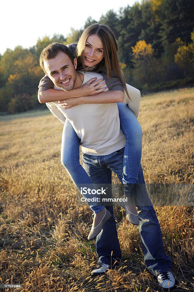 Young smiling couple playing in autumn surroundings Young couple playing in fall forest surroundings. Adults Only Stock Photo