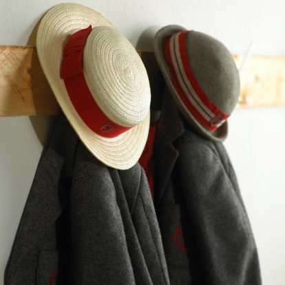 traditional school hats and blazers hanging on pegs