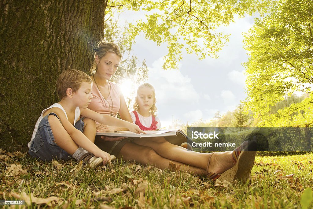 Family reading Mother reading a book with her son and daughter Nanny Stock Photo