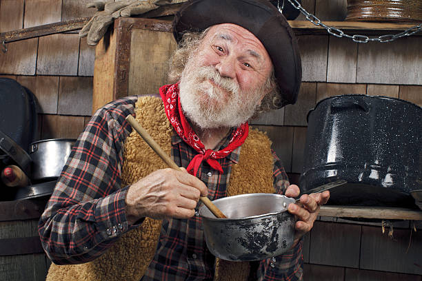istock Old cowboy stirs saucepan in outdoor kitchen 177535978