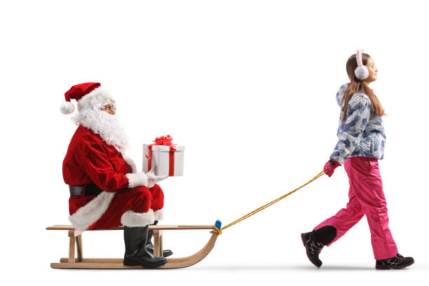 istock Santa claus holding a present and sitting on a sled pulled by a girl 1775361391