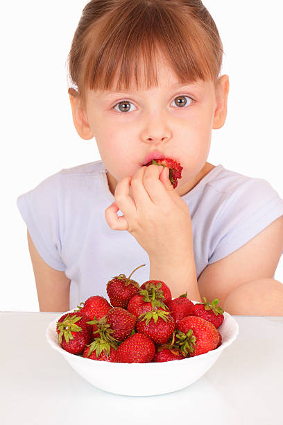 Beautiful little girl eating tasty strawberries stock photo